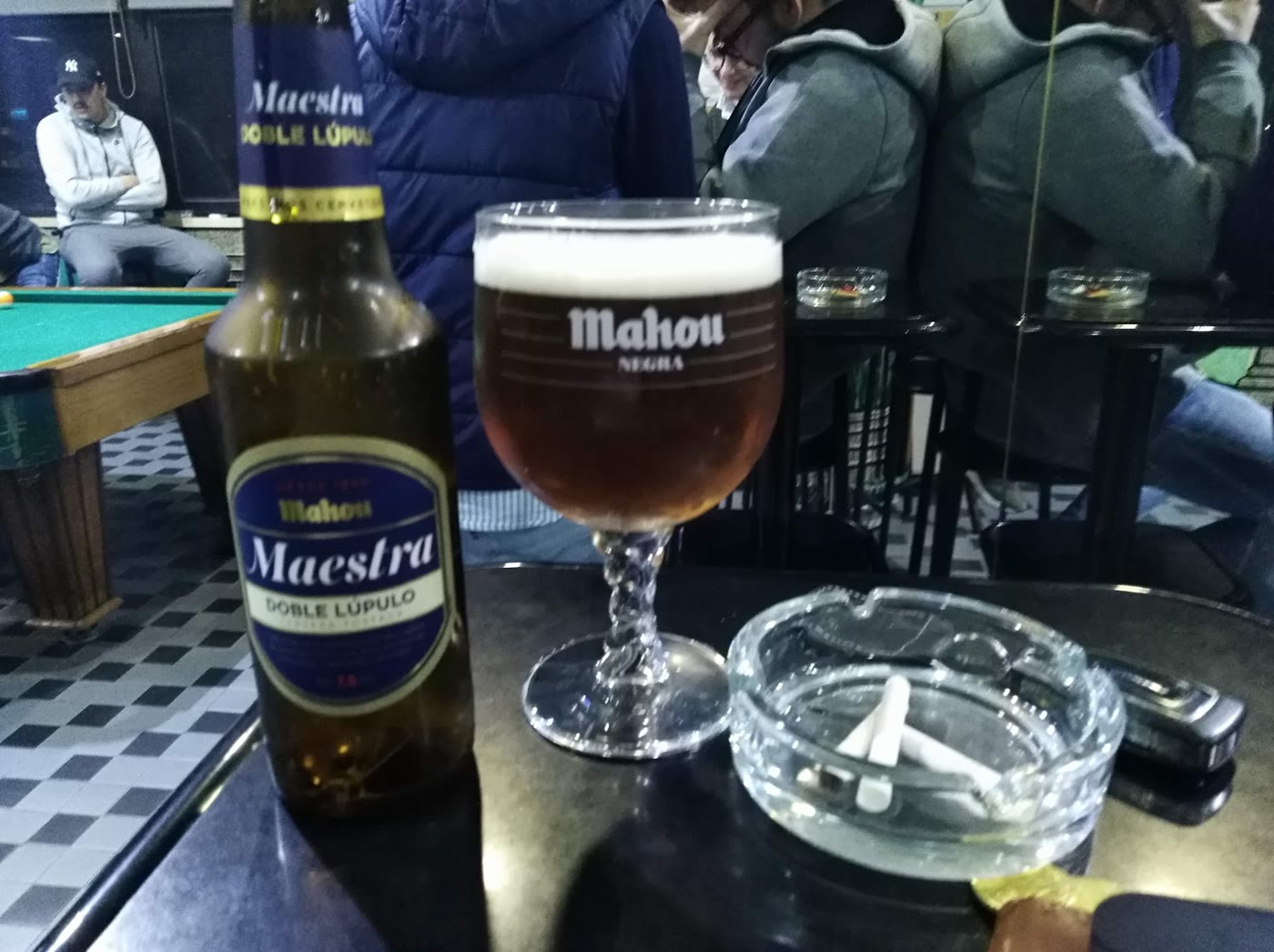 Uma mesa de bilhar de pano verde ao lado das mesas do café